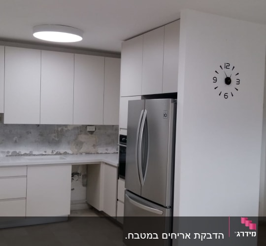 מטבח בשיפוץ עם קיר חשוף וארונות חדשים